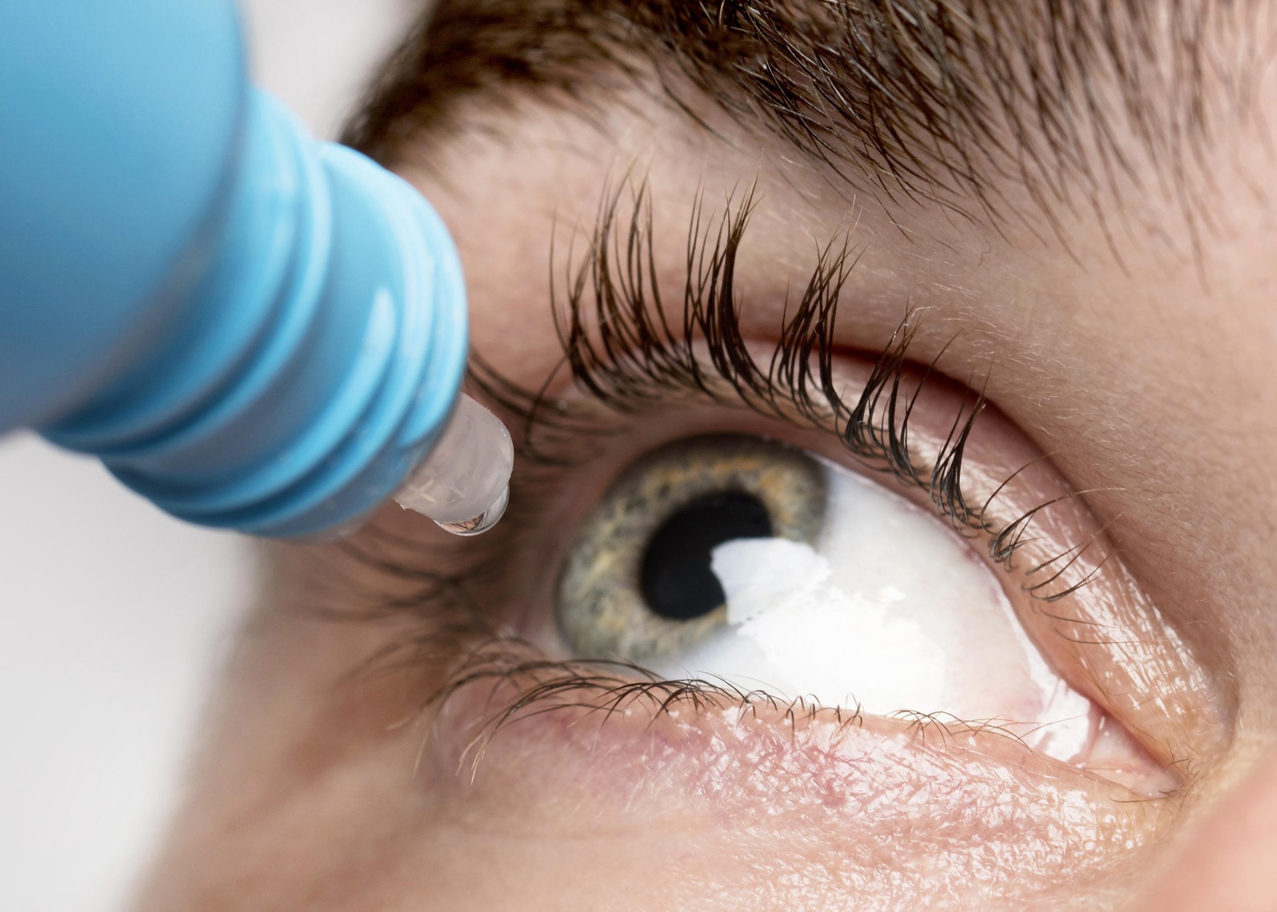 man using eye drops close up